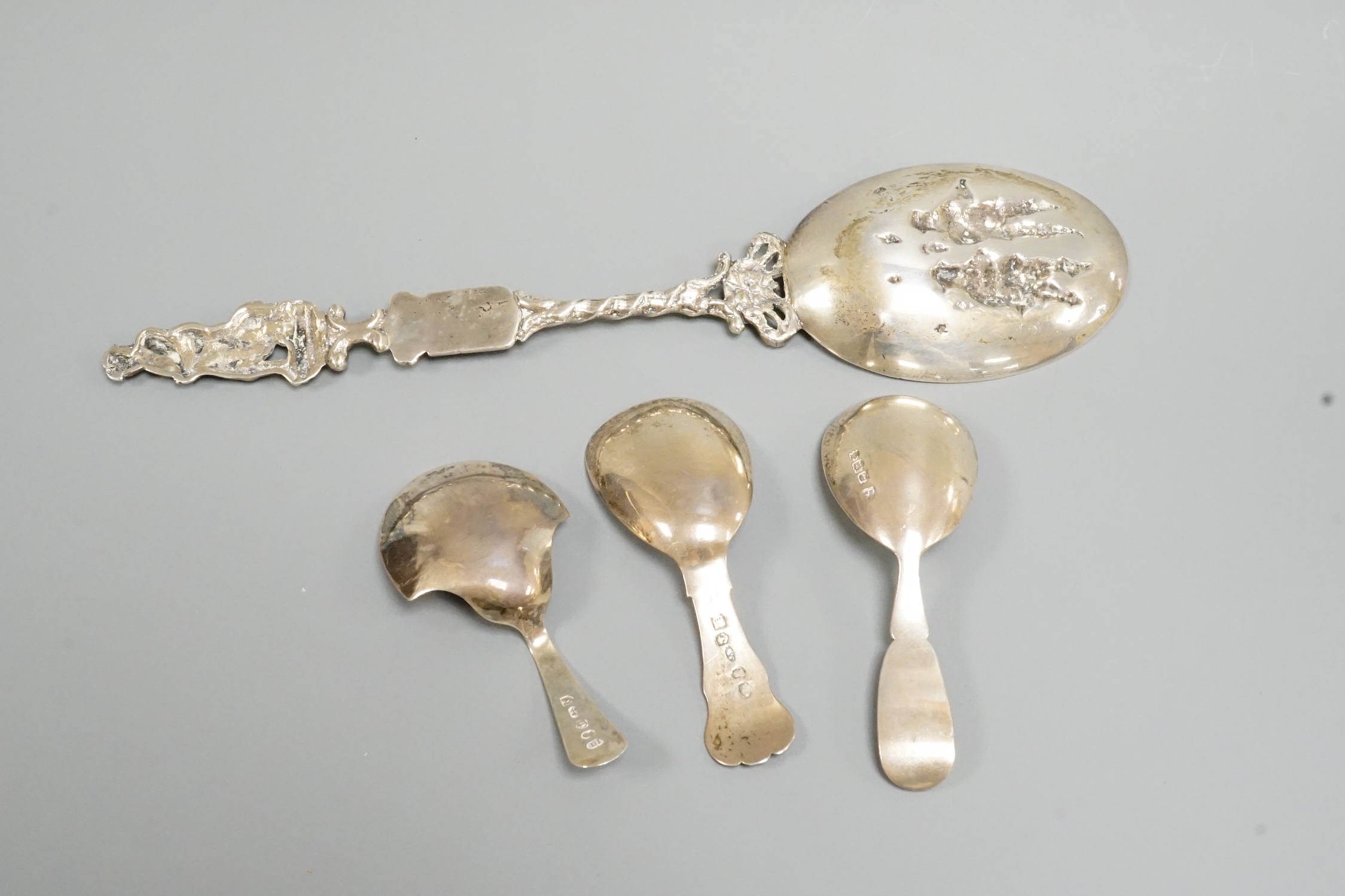 Two 19th century silver caddy spoons, including Birmingham, 1827, one later caddy spoon and an ornate Dutch white metal serving spoon.